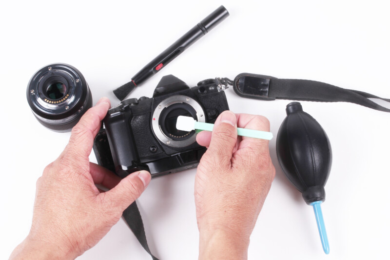 cropped hands photographer cleaning camera white background